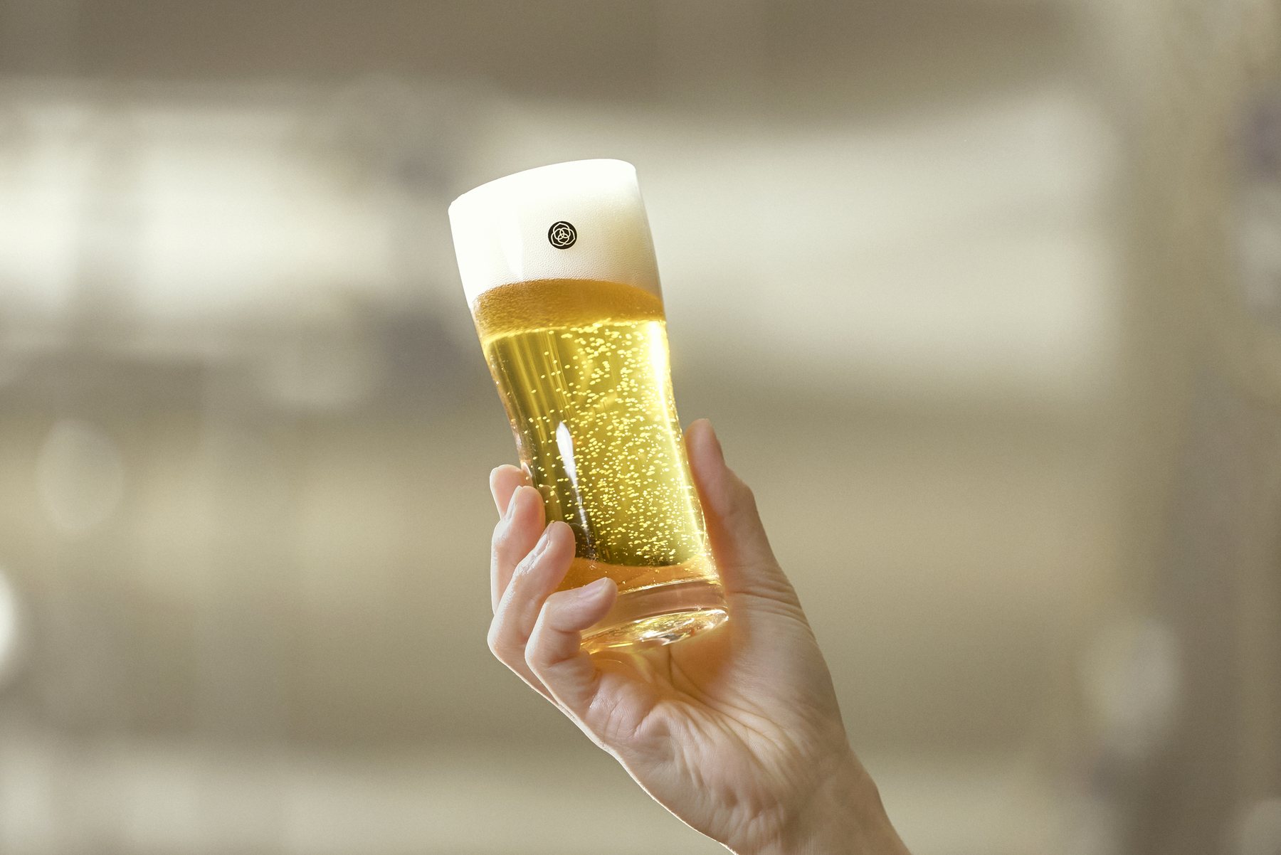 明るい光の中で掲げられたCOEDOのビールグラス
