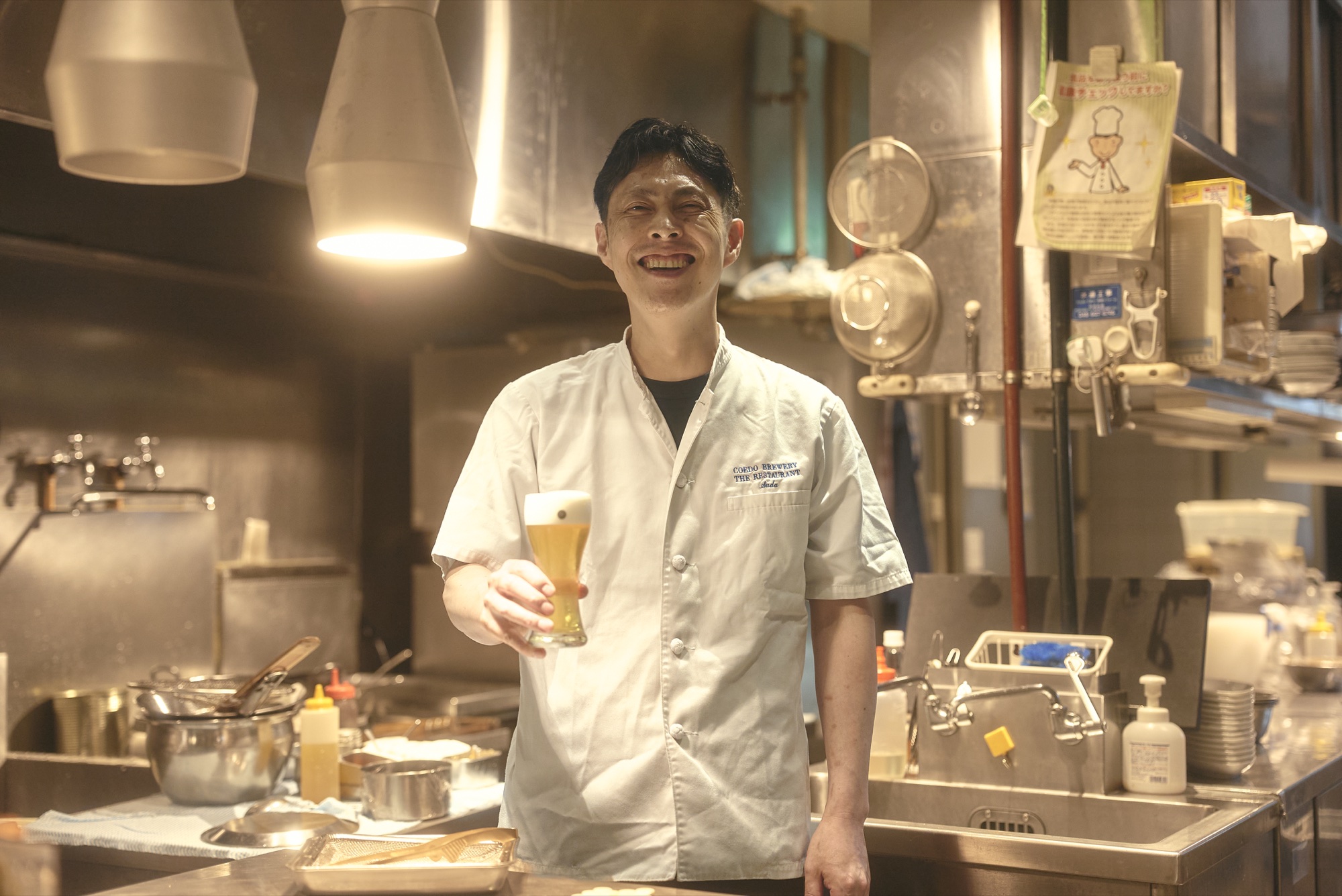 シェフが厨房でビールを手にする様子